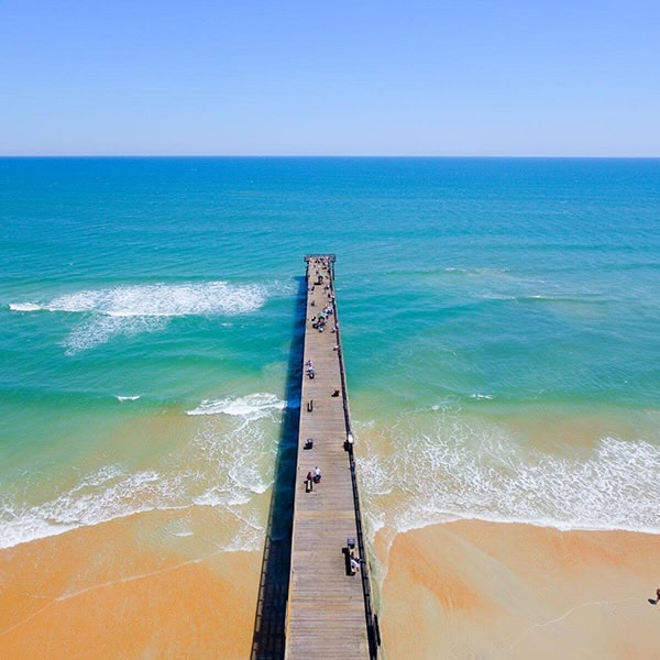 A long pier on a clean beach, ideal for dog training in St. Augustine Beach, FL.